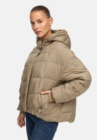 Beige pufferjack met een capuchon, gequilt ontwerp, voorkeursluiting en zijzakken. Bevat een logo-opdruk op de linker mouw.