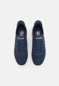 Scarpe da ginnastica blu navy con tomaia in rete, suola flessibile e lacci elastici. Progettate per la comodità di indossarle facilmente, con una soletta imbottita.