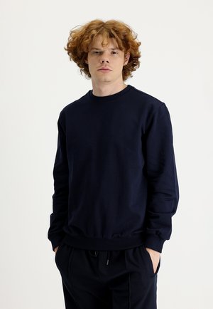 Sudadera de algodón de color azul marino con mangas largas, cuello redondo y puños y cintura acanalados. Presenta una textura suave y un diseño minimalista.