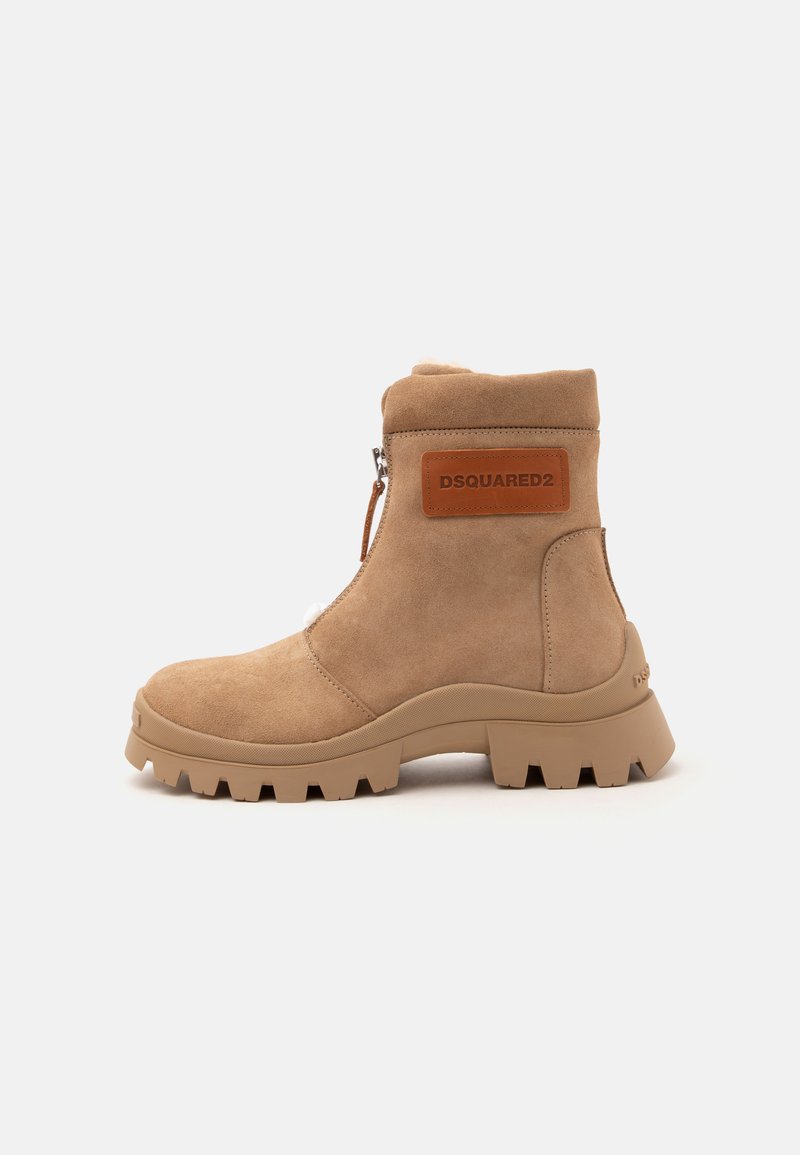 Bottine beige en daim avec semelle épaisse, fermeture éclair latérale et patch en cuir marron marqué "DSQUARED2" sur le côté extérieur.