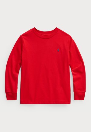 Camiseta roja de manga larga hecha de algodón con cuello redondo. Presenta un pequeño logo azul en el pecho y puños de canalé. Textura suave.
