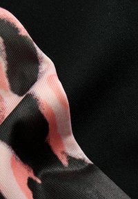 Un tissu à motif affichant un design abstrait rose et noir, contrasté par un matériau noir texturé, mettant en valeur la couleur et la texture.