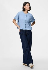 Light blue knitted cardigan with short sleeves, ruffled edges, and button closure; paired with dark blue wide-leg jeans and white sneakers.