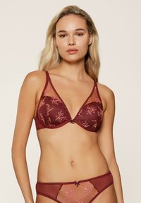Maronde bh en slipset met bloemmotieven, doorschijnende panelen en een driehoekige vorm; satijnachtige textuur met strikaccenten.