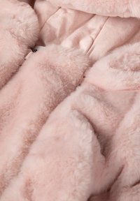 Tessuto in pelliccia artificiale di un delicato rosa con una superficie soffice e testurizzata. Presenta un rivestimento interno liscio di un rosa leggermente più scuro.