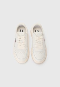 Vita lädersneakers med beige sulor, rund tå, platta snören, perforerade detaljer och små varumärkesaccenter på sidan.