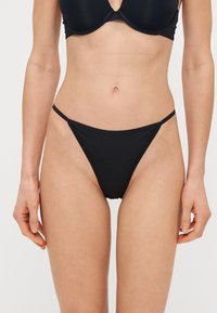 Sort bikini med et minimalistisk design, der har tynde sidestropper og en tætsiddende pasform. Fremstillet af glat stof med en elegant finish.