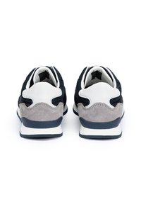 Černé a šedé sportovní boty s vrchní částí z semiše, bílými akcenty a texturovanou podrážkou, z pohledu zezadu, s viditelnými detaily šněrování a designu.