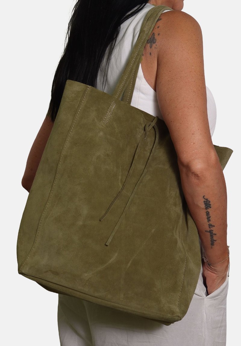 Borsa tote in suede verde oliva con due manici, una consistenza morbida e chiusura con coulisse. Forma grande e quadrata con minimi dettagli di cucitura.