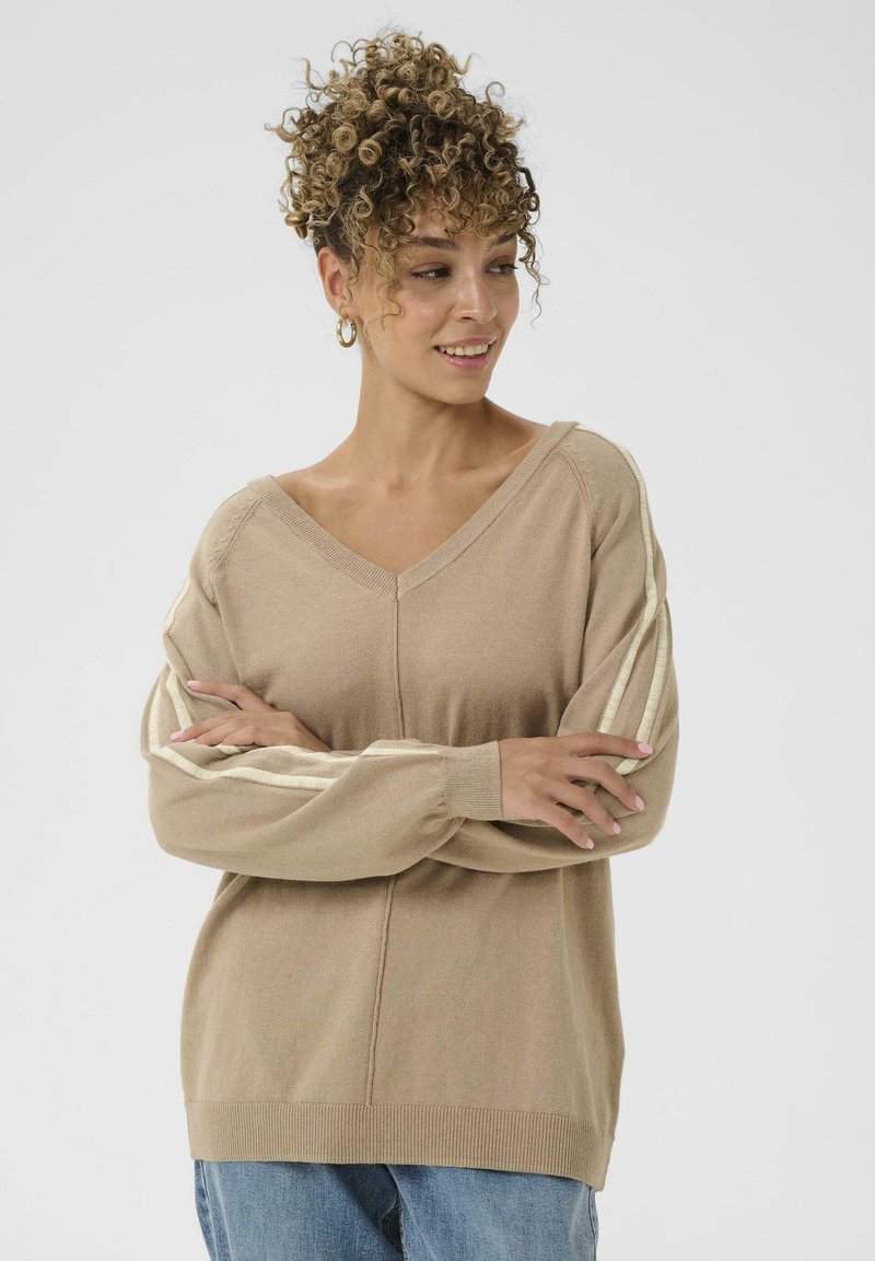 Beige Strickpullover mit V-Ausschnitt, langen Ärmeln und weißen vertikalen Streifen auf den Schultern. Weicher Stoff und lässige Passform.