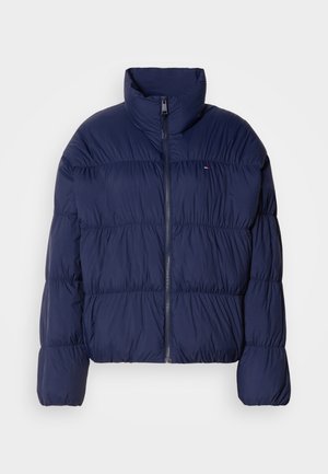 Doudoune bleu marine avec un col haut, fermeture éclaire, design matelassé et poignets élastiques. Comprend un petit logo sur la poitrine gauche.