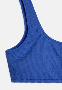 Blå ribbet bralette med brede stropper, teksturert materiale og sømløst design. Har en myk, elastisk finish for komfort.