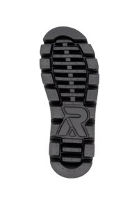 Suela de zapato de goma negra con un patrón de relieve texturizado, que presenta surcos profundos, acentos circulares y un diseño de logo en el centro.