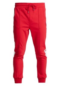 Pantaloni sportivi rossi con vita regolabile, tasche laterali e accenti bianchi sui lati. Realizzati in tessuto elastico e liscio.