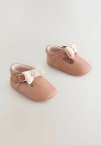 Baby shoes featuring soft pink leather, rounded toe, side strap with buckle detail, and a decorative bow on the front.