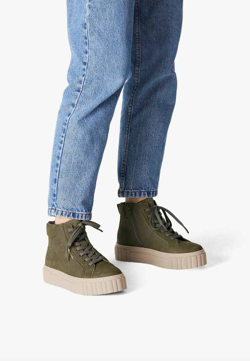Baskets montantes en daim vert olive avec un extérieur texturé, bout rond, semelle plateforme plate et lacets gris. Comprend un détail de fermeture éclair sur le côté.