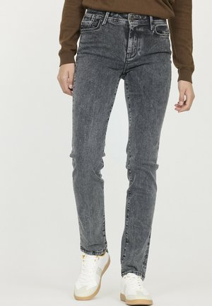 Jean en denim gris taille haute avec une finition délavée, jambe droite, poches avant et fermeture à un bouton, associés à des baskets blanches.