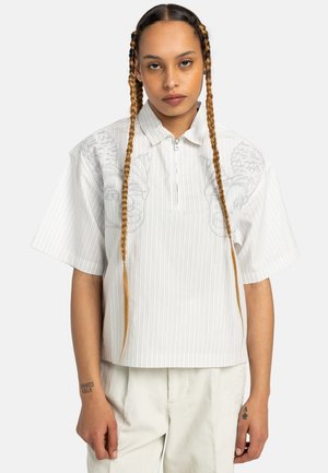White short-sleeve shirt with vertical stripes, half-zip collar, and embroidered light grey patterns on the front. Minimalist design.