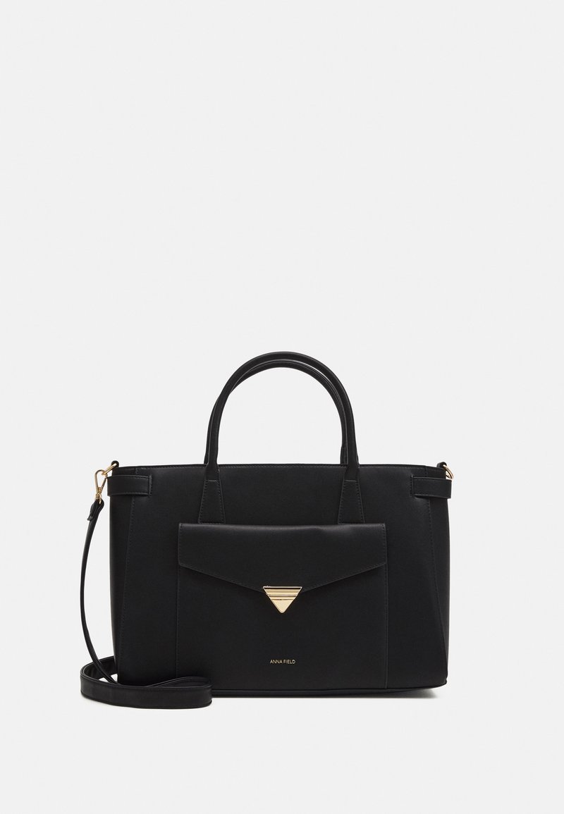 Sac à main rectangulaire noir avec poignées supérieures, poche avant à rabat avec fermoir triangulaire doré, et bandoulière amovible sur fond uni.