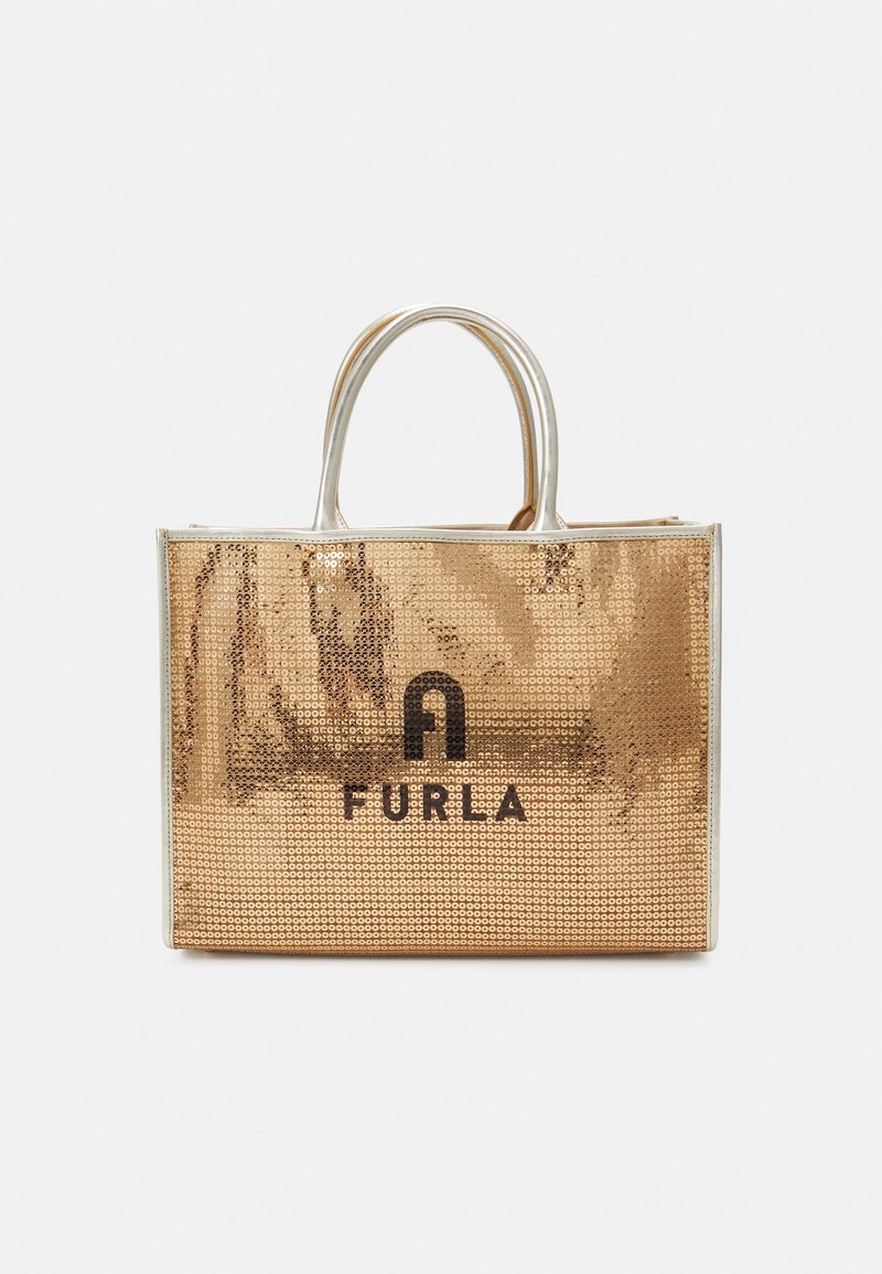 Złota torebka typu tote z cekinami, z srebrnymi uchwytami i logo Furla umieszczonym na środku przedniego panelu na białym tle.