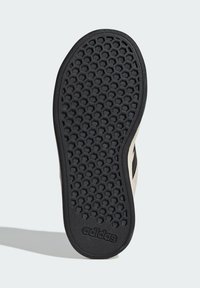 Svart gummisål med ett bikakestruktur, med en krämfärgad sida och svarta accenter. "Adidas"-logotyp präglad på hälen.