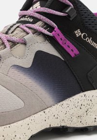 Buty turystyczne Columbia z szaro-czarną cholewką o teksturowanym wykończeniu, fioletowymi sznurówkami i cętkowaną beżową podeszwą.