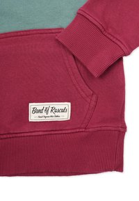 Maroon sweatshirt with ribbed cuff, kangaroo pocket, and a label reading "Band of Rascals Finest Organic Kids Clothes" near the hem.