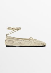 Ballet flats in pelle di serpente beige con lacci alla caviglia, punta affusolata e suola piatta nera, caratterizzate da una superficie testurizzata e un design minimalista.