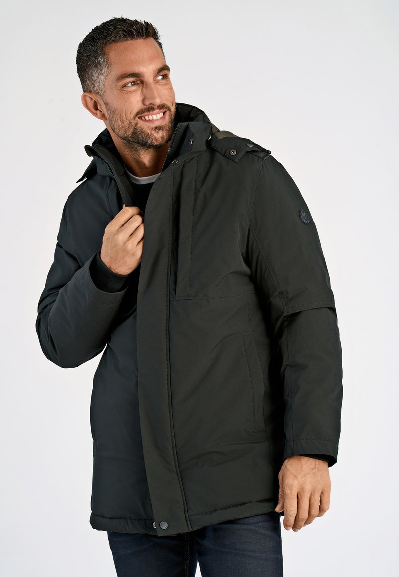 Mörkgrön isolerad jacka med dragkedja framtill, avtagbar huva och tryckknappar. Har en bröstficka och sidofickor för händerna.