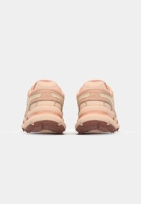 Světle růžové sportovní boty s prodyšným síťovaným svrškem, polstrovanou podrážkou a gumovou trakční podrážkou, navržené s zakřiveným siluetem.