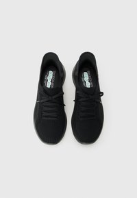Pair of black Skechers slip-in athletic shoes with knit fabric upper and laces, viewed from above on a plain background.