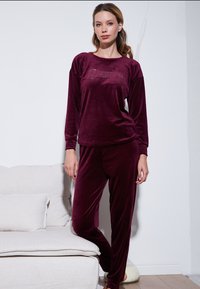 Burgundy velvet loungewear set featuring a long-sleeve top with "follow your Dreams" text and matching pants, soft texture, fitted design.