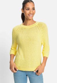 Gelber Strickpullover mit rundem Ausschnitt, Dreiviertelärmeln und geripptem Saum, kombiniert mit hellblauen Jeans.