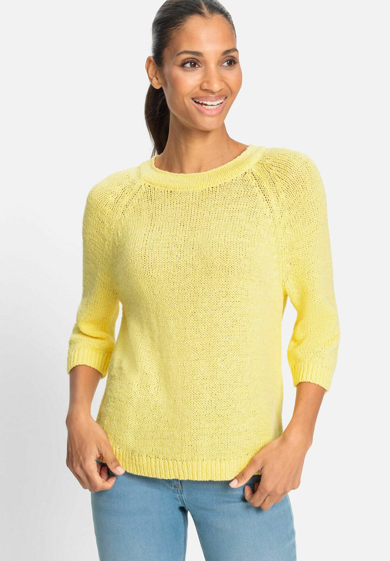 Gelber Strickpullover mit rundem Ausschnitt, Dreiviertelärmeln und geripptem Saum, kombiniert mit hellblauen Jeans.