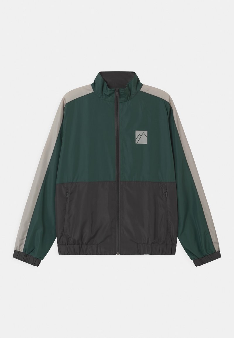 Veste coupe-vent en vert foncé, noir et gris. Dotée d'une fermeture éclair, d'un col montant et d'un petit logo dans le coin supérieur gauche.