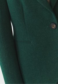 Blazer verde in lana con trama a spina di pesce, caratterizzato da un bottone singolo, rever a incavo e una tasca laterale elegante.