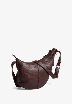 Sac bandoulière en cuir bordeaux avec une forme incurvée, surface texturée et fermeture éclair. Comprend une sangle réglable.
