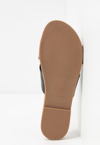 Vue de la semelle d'une chaussure noire avec une semelle en caoutchouc couleur fauve présentant de fines rainures horizontales et la marque New Look taille 4/37.