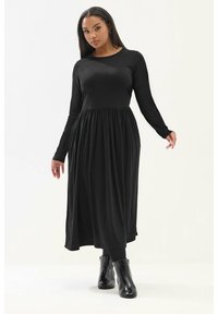 Musta pitkähihaista mekkoa, jossa on tiukka bodice ja levenevä hameosa, valmistettu pehmeästä kankaasta, pyöreällä kaula-aukolla ja nilkkoihin ulottuvalla helmallä.