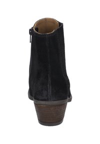 Bottine en suede noir avec un petit talon, dotée d'une fermeture éclair à l'arrière et de coutures le long des coutures. Texture lisse avec un bout arrondi.