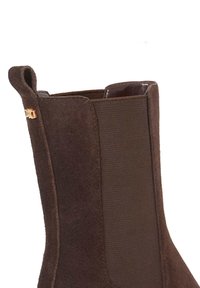 Brown suede ankle boot with elastic side panels, a smooth interior, and a gold hardware accent near the heel.