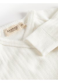 Vitt ribbat tröja med V-ringning, med texturerade mönster. Etikett synlig med varumärket "MarMar COPENHAGEN" och storlek "56".
