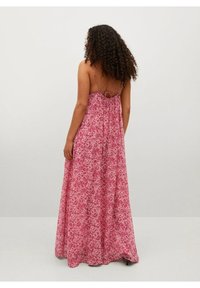 Robe maxi à motif floral rose, dotée de fines bretelles et d'un détail découpé dans le dos. Fabriquée en tissu léger et fluide.