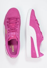 Baskets en daim rose avec accents blancs, bout arrondi, semelle plate et lacets texturés. Logo PUMA en or sur le côté et la languette.