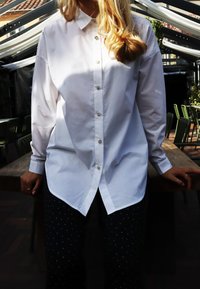 Valge särgiga nuppudega, terava kraega, veidi üle suuruse, läikivate nuppudega. Kandja pimedates pükstes, mis on kaetud väikeste täppidega.