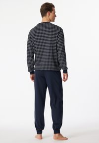 Navy long-sleeve pajama top with a white grid pattern, paired with solid navy pants. Soft fabric with ribbed cuffs. Model shown from the back.