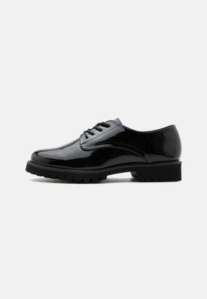 Chaussure à lacets en cuir noir brillant avec semelle épaisse texturée, talon bas et bout arrondi, vue de côté sur un fond uni.