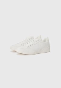 White sneakers featuring a smooth leather upper, textured accents, padded collar, and flat rubber sole with a minimalist design.