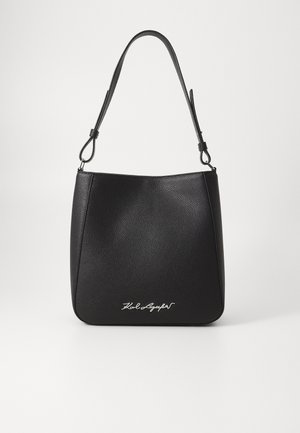 Bolso de hombro de cuero negro con textura, con correa ajustable y un detalle metálico del logo en el centro frontal.