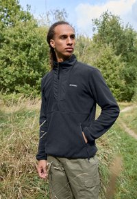 Sort fleece pullover med halvlængde lynlås og sidelommer. Har en tekstureret overflade og Columbia-logo på brystet.